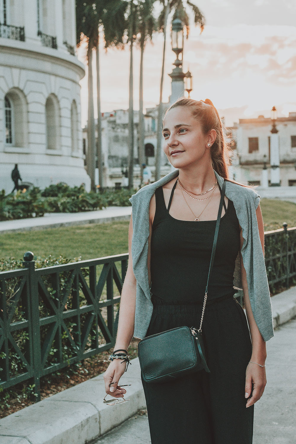 Woman in a green jacket on a palm-lined promenade