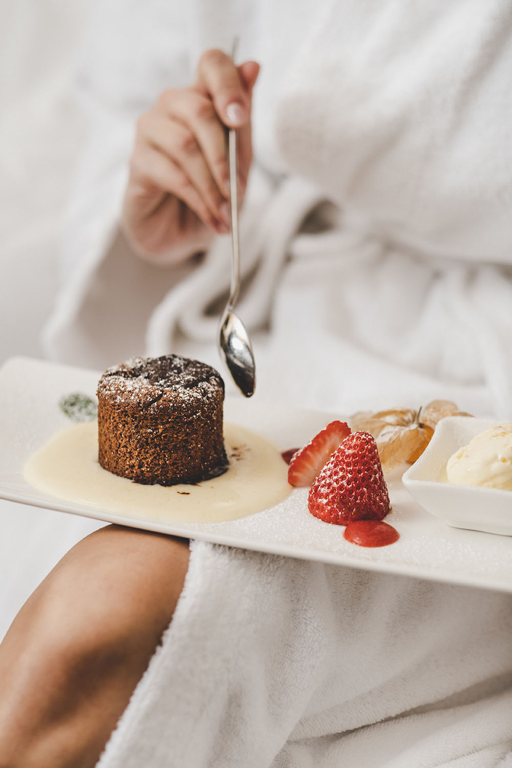 Chocolate lava cake with strawberries served on a tray in bed