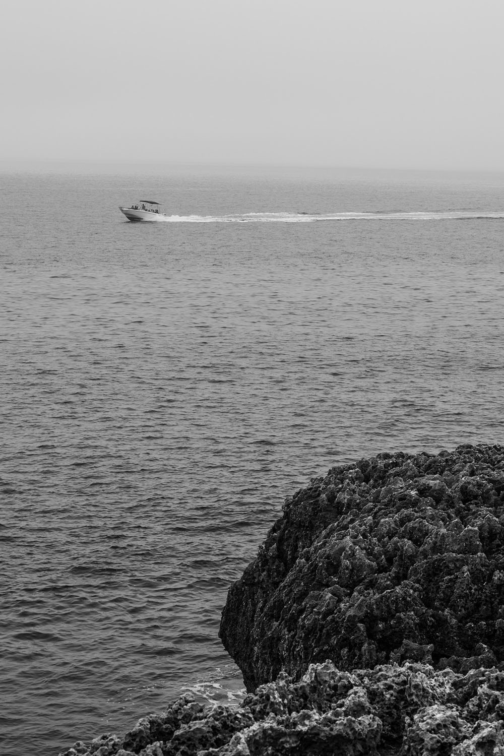 Motorboat on the open sea, seen from a rocky shore